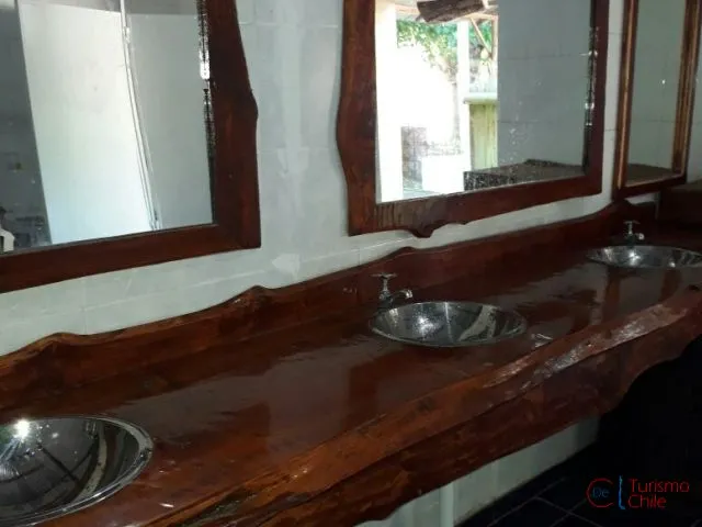 Baños con mesón de madera nativa artesanal y lavamanos en Camping Porvenir