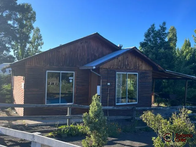 Cabaña de madera con cielo azul y jardín en Camping y Cabañas Porvenir